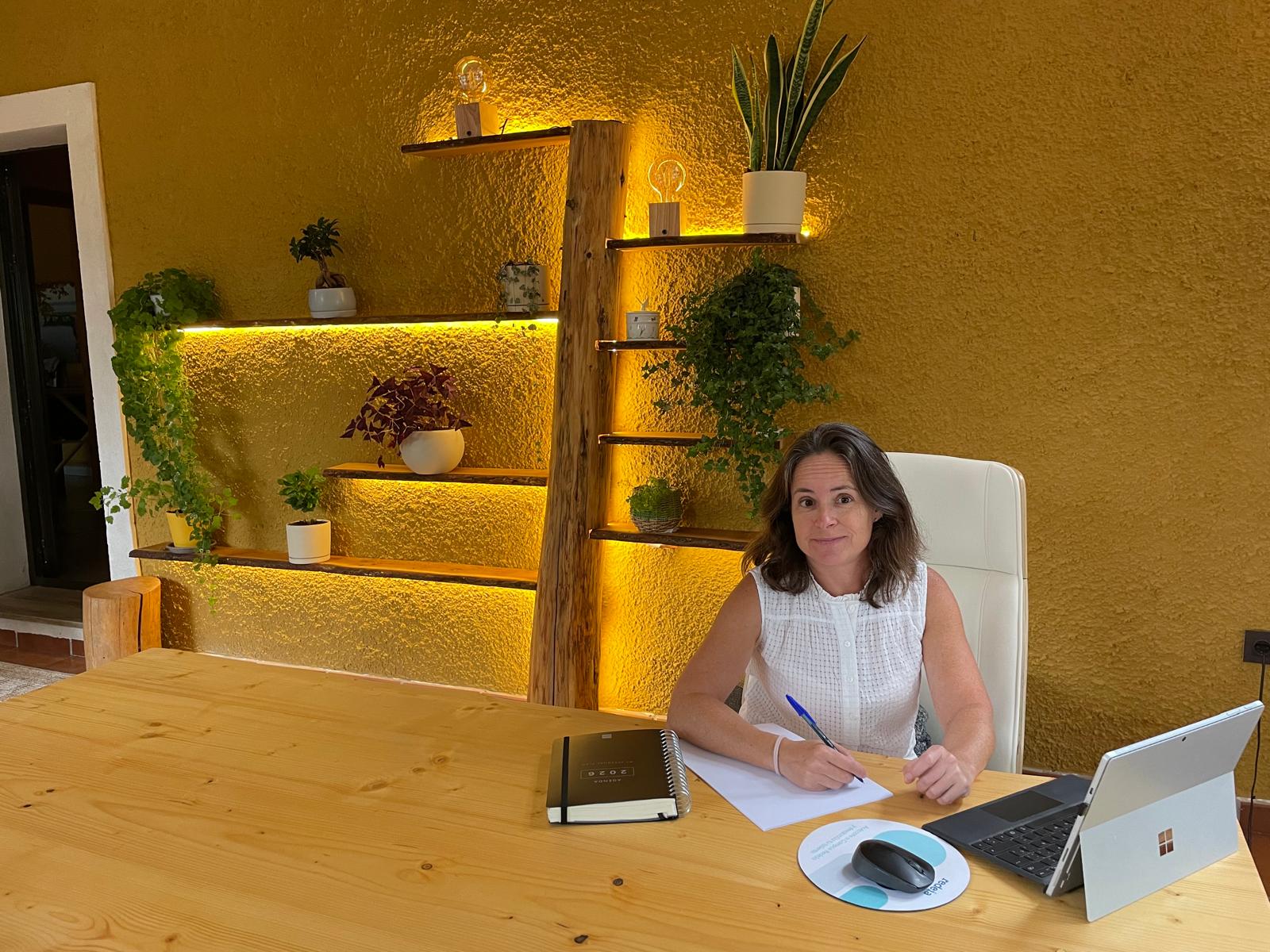 Arancha en su consulta, junto a la mesa de madera