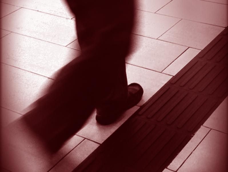 Sombra de una persona caminando sobre un suelo de baldosas