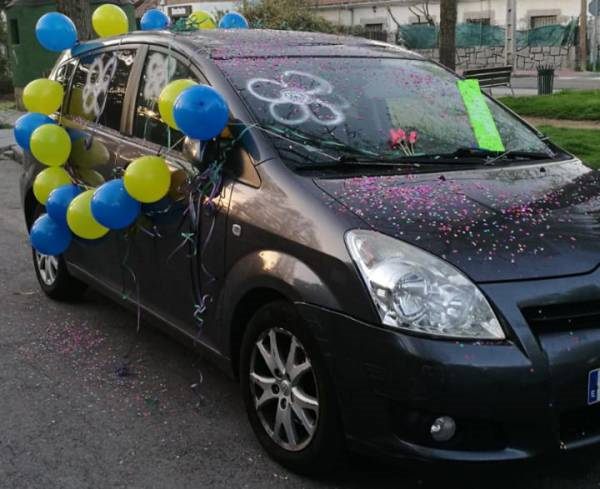 Coche decorado con globos azules y amarillos y confeti